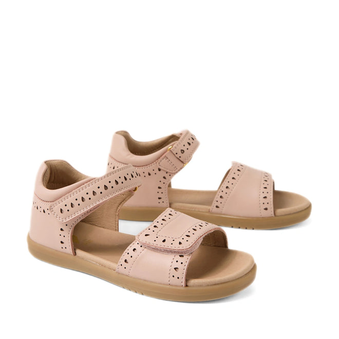 A pair of Bobux Kid+ Plus KP Logan Cameo Rose Pink Open Toe Sandals for girls, featuring light brown soles, stylish cut-out patterns, and adjustable Velcro straps over the toes and around the ankles. These leather sandals provide both comfort and style for little feet.