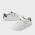 A pair of Bobux Kid+ Plus KP Maverick Leather Sneakers in White Navy—children’s sneakers with adjustable velcro straps, dark blue heel accents, and crafted from breathable leather for comfort—are stylishly displayed on a white background.