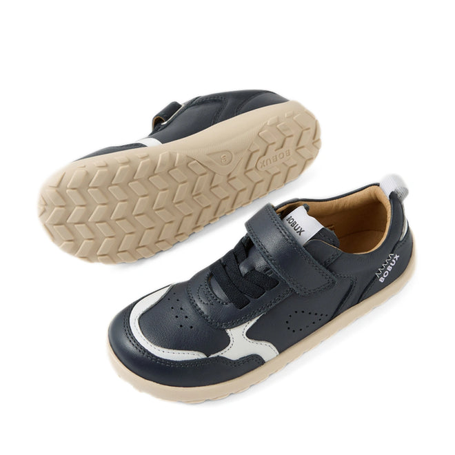 A pair of Bobux Kid+ Plus KP Neo Leather Sneaker Navy Alpha for kids is shown from the side and bottom. These navy blue leather sneakers feature white soles and accents, a barefoot-shaped toebox, a Velcro strap, and toe perforations for enhanced breathability., 9420074847690, 9420074847706, 9420074847713, 9420074847720, 9420074847737, 9420074847744, 9420074847751