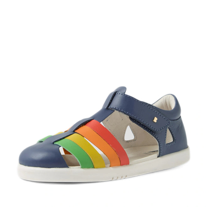 The Bobux Kid + Plus Tidal Closed Toe Quick Dry Sandal in Vintage Indigo Blue is a children’s sandal featuring cutouts and vibrant rainbow-colored straps (red, orange, yellow, green) on the side, paired with a white sole. Crafted from water-friendly leather, these closed-toe sandals are perfect for any adventure and offer both comfort and eye-catching style inspired by the iconic Bobux design., 9420074809605, 9420074809612, 9420074809629, 9420074809636, 9420074809575, 9420074809582, 9420074809599