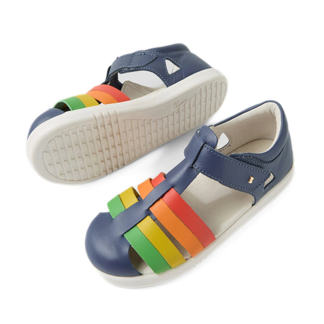 Two pairs of Bobux Kid + Plus Tidal Closed Toe Quick Dry Sandals in Vintage Indigo Blue, designed for kids. These sandals feature blue uppers, water-friendly leather construction, white soles, and colorful straps in green, yellow, orange, and red across the toes. A Velcro strap ensures easy fastening—perfect for active little ones on the go., 9420074809605, 9420074809612, 9420074809629, 9420074809636, 9420074809575, 9420074809582, 9420074809599