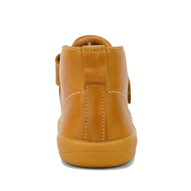 The Bobux Kid+ Desert Boot Caramel 830305Z heel view is a brown leather unisex children’s high-top boot with a tan rubber sole and wide hook-and-loop strap, shown in side profile against a white background., 9420068516861, 9420075719682, 9420075719699, 9420068516892, 9420068516908, 9420068516915, 9420068516922