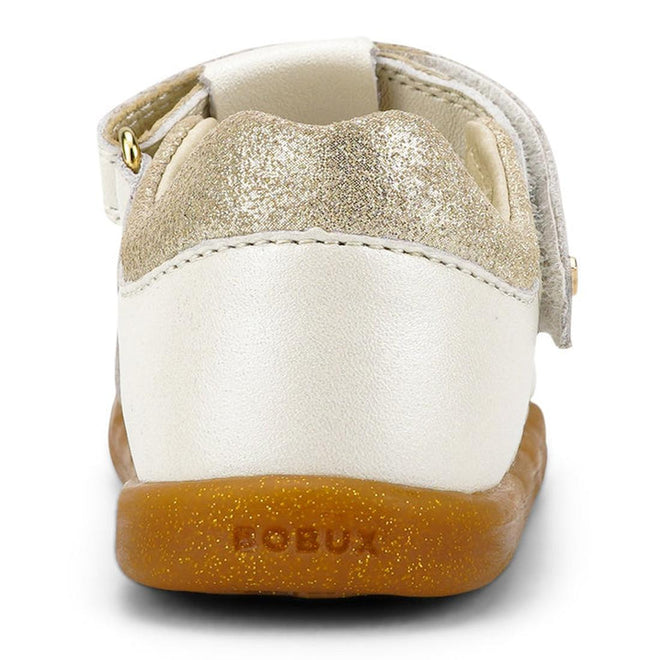A close-up rear view of the Bobux iwalk Cross Jump Sandal Moon Pearl Closed Toe 636708 shows a gold glitter heel, white leather upper, brown rubber sole, Velcro strap, and "BOBUX" embossed on the heel., 9420068516335, 9420068516342, 9420068516359, 9420068516366, 9420068516373