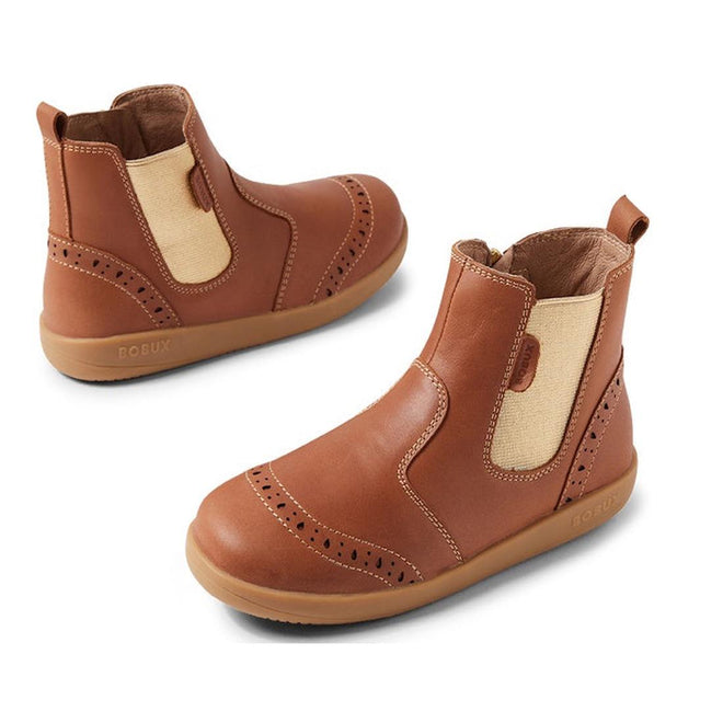 The Bobux Kid+ KP Billie 2 II Girls Leather Boot in Caramel Tan for juniors features tan elastic side panels, decorative perforations, a convenient zipper closure, and flexible rubber soles—shown from a side and angled view.