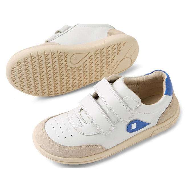 The Bobux KP Kids Plus Champ II Sneaker White Blue Juniors features white leather, beige soles and toe caps, blue accents on heel and side, and two Velcro straps. One shoe is upright; the other is on its side showing the durable sole., 9420074829924, 9420074829931, 9420074829948, 9420074829955, 9420074829962