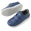 The Bobux KP Kids Plus Grass Court II Leather Sneaker in Vintage Indigo Blue features two adjustable straps, white soles, subtle perforations on the sides, and a textured sole, shown with one shoe upright and the other on its side., 9420074859440, 9420074859457, 9420074859464, 9420074859471, 9420074859488, 9420074859495, 9420074859501