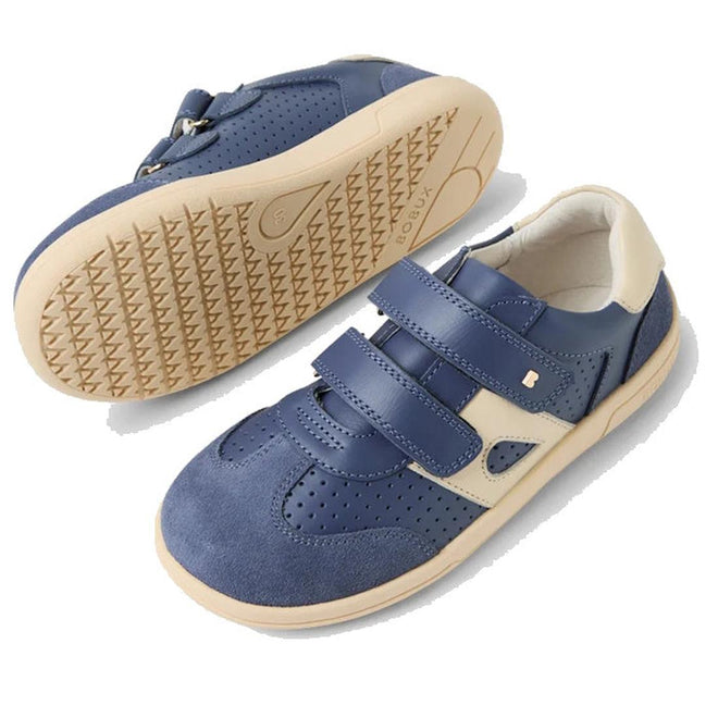 The Bobux KP Kids Plus Titan Juniors Leather Sneaker in Vintage Indigo Blue features adjustable straps, perforated detailing, and a durable beige rubber sole. One shoe is upright; the other lies on its side to show the tread pattern., 9420074855824, 9420074855831, 9420074855848, 9420074855855