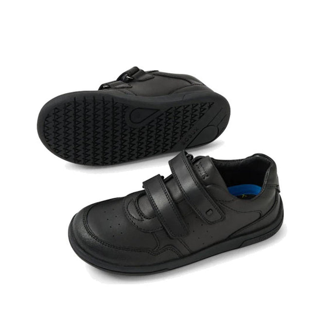The Bobux Kid+ Scoot Black School Leather Sneaker Shoe features Velcro straps and a durable, textured sole—one shoe stands upright showing the top and side, while the other lies on its side, highlighting everyday school-ready comfort.