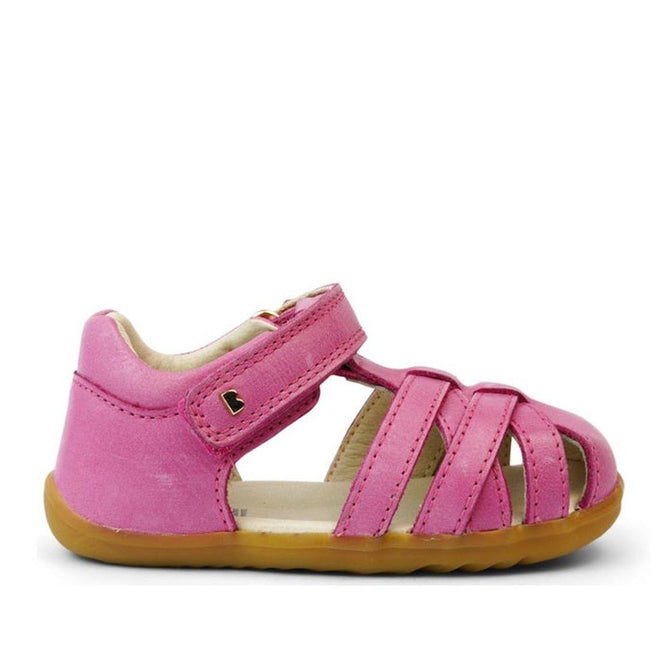 The Bobux Step Up Toddlers Cross Jump Sandal Bright Pink 731109 features pink leather, a tan rubber sole, open toe, Velcro strap, multiple front straps, and a metallic heart detail—perfect as a first walker., 9420068531420, 9420068531437, 9420068531444, 9420068531451