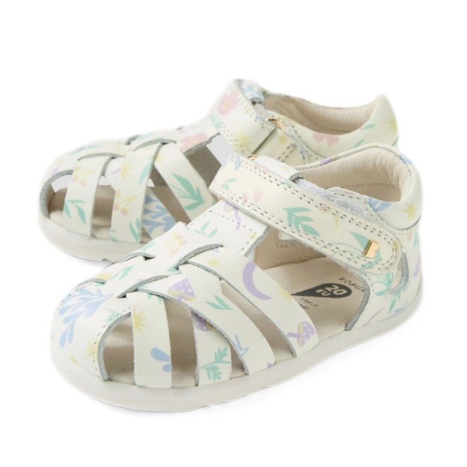 A pair of Bobux Step Up SU Tropicana II White Floral Closed Toe Sandal for toddlers featuring a closed toe, crisscross straps, and a pastel floral pattern. These leather sandals offer a convenient hook-and-loop strap for easy fastening and comfortable white soles.