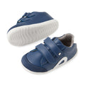 Bobux SU Step Up Blaze Leather Toddlers Sneaker in Vintage Indigo features quick-drying blue leather uppers, white flexible soles, easy Velcro straps, and a soft grey lining. Shown with one sneaker upright and the other on its side to display the bendable sole—these first walkers are perfect for little ones taking their first steps., 9420074848758, 9420074848765
