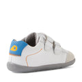 The Bobux SU Step Up Blaze Leather Toddlers Sneaker in White Orange features gray soles, blue and yellow heel accents, orange stitching, double Velcro straps, and suede toe detailing—angled to highlight both the side and back. These leather sneakers are an ideal choice for your toddler’s first walking shoes., 9420074848789, 9420074848796, 9420074848802, 9420074848819