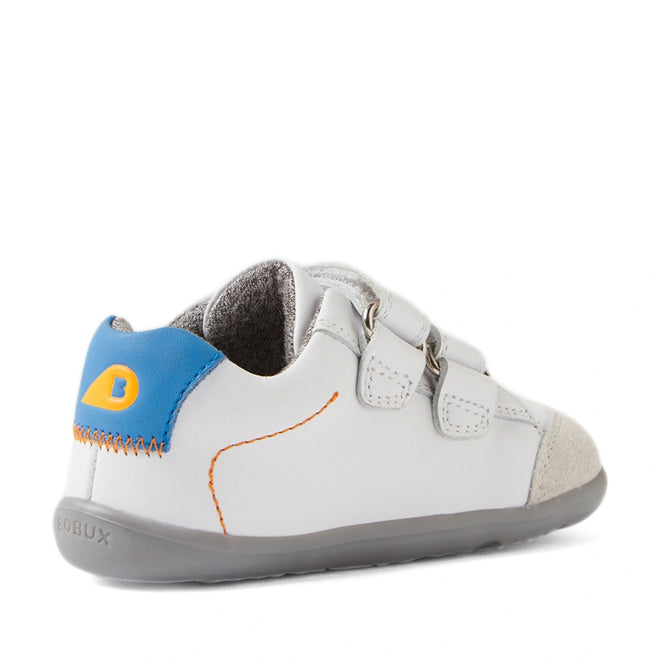 The Bobux SU Step Up Blaze Leather Toddlers Sneaker in White Orange features gray soles, blue and yellow heel accents, orange stitching, double Velcro straps, and suede toe detailing—angled to highlight both the side and back. These leather sneakers are an ideal choice for your toddler’s first walking shoes., 9420074848789, 9420074848796, 9420074848802, 9420074848819