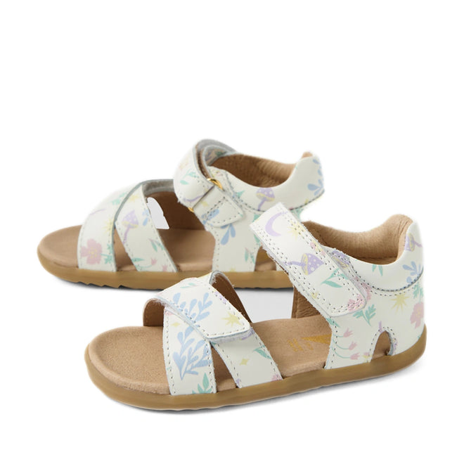 The Bobux Step Up Flora First Walker Sandal in White Floral is a pair of children’s open-toe, open-heel leather sandals featuring pastel-colored floral and plant patterns on a white background, beige soles, and adjustable straps—perfect as little ones’ first walking sandals.