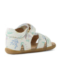 The Bobux Step Up Flora First Walker Sandal in White Floral features a pale floral print, an open-toe design, a tan sole, and a side buckle. Seen from the back and side to showcase the heel and straps, these leather sandals offer both style and support—perfect for little feet taking their first steps.