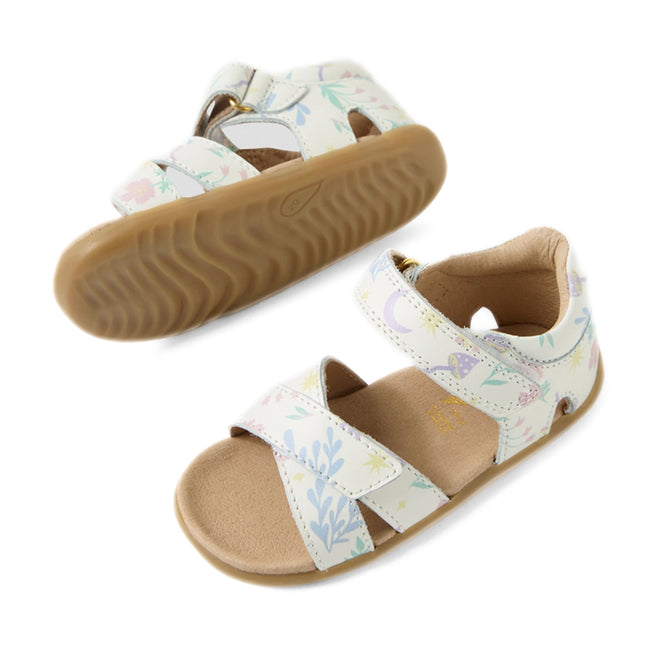 The Bobux Step Up Flora First Walker Sandal in White Floral features two children’s sandals with tan soles and white leather straps adorned with a pastel floral pattern. One sandal is upright, revealing the top and side, while the other is shown upside down to display its textured sole—making them perfect as baby sandals or first walking leather sandals for your little one.