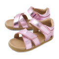 The Bobux Step Up Flora First Walker Sandal in Pink Lemonade Metallic is a pair of open-toe children’s sandals featuring leather metallic pink straps and tan soles. Designed for first walkers, these sandals include adjustable hook-and-loop closures at the ankle and across the toes, ensuring a secure and comfortable fit.
