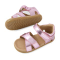 Two pairs of Bobux Step Up Flora First Walker Sandal in Pink Lemonade Metallic for toddlers, with tan soles, velcro straps, and open toes, displayed on a white background.