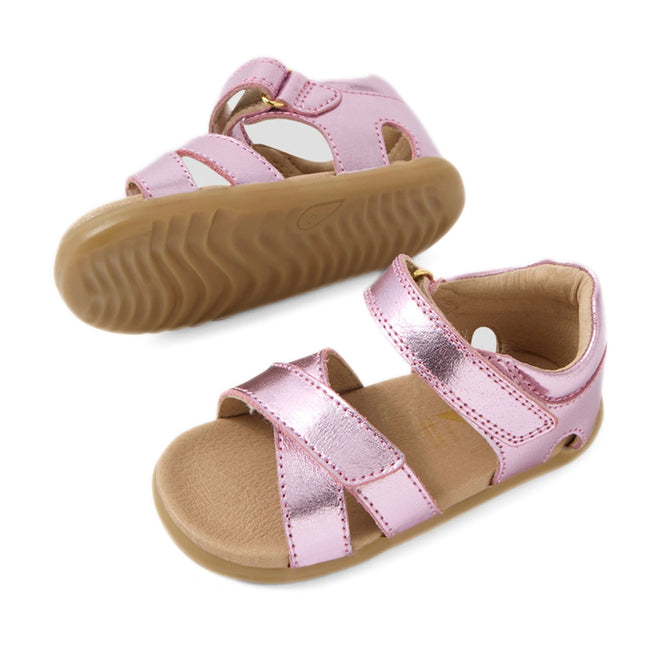 Two pairs of Bobux Step Up Flora First Walker Sandal in Pink Lemonade Metallic for toddlers, with tan soles, velcro straps, and open toes, displayed on a white background.
