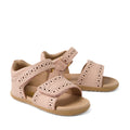 Bobux Step Up Grass Logan First Walker Sandal in Cameo Rose Pink—girls’ leather sandals featuring decorative cutout patterns, adjustable ankle and toe Velcro straps, and tan soles, displayed on a white background. Perfect as stylish first walker sandals.