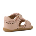Bobux Step Up Grass Logan First Walker Sandal in Cameo Rose Pink—first walker girls’ leather sandals with decorative cutouts, a closed heel, open toe, ankle strap with gold buckle, and a flexible tan rubber sole; shown from the back left side.