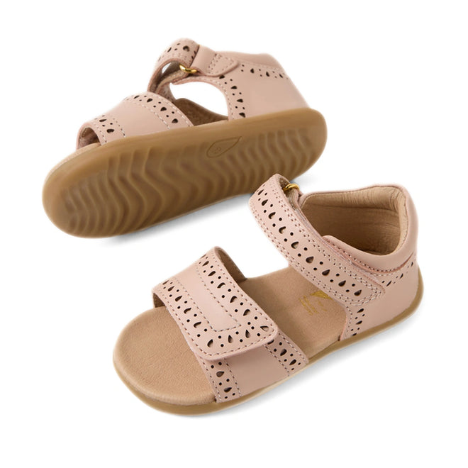 The Bobux Step Up Grass Logan First Walker Sandal in Cameo Rose Pink is a pair of girls’ leather sandals with Velcro straps, decorative cutouts, and tan rubber soles—perfect as stylish first walker sandals.