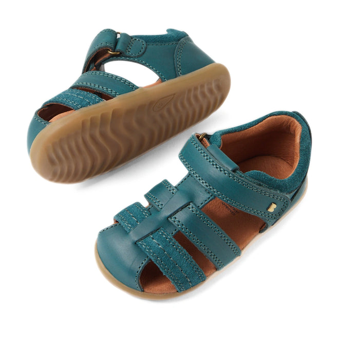 A pair of Bobux Step Up Sandal Roam Closed Toe Sandals in Mediterranean Green, featuring tan rubber soles, velcro straps, and closed toes. Crafted from durable leather, one sandal is upright while the other shows off the distinctive wavy tread pattern on the sole., 9420074807144, 9420074807151, 9420074807168, 9420074807175