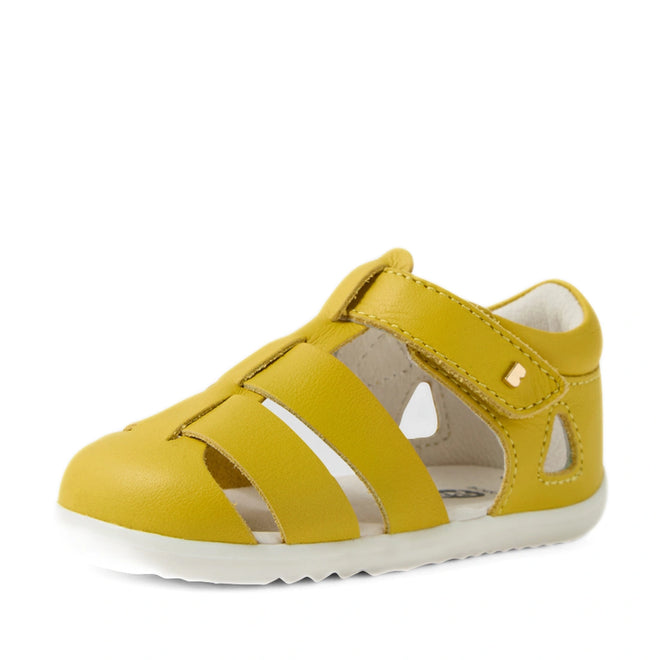 A Bobux Step Up SU Toddlers Tidal Mango Mint Yellow Closed Toe Sandal, featuring water-friendly leather in vibrant yellow with cut-out sides, a Velcro strap, and a white rubber sole—ideal as a first walker shoe—is displayed at an angle on a plain white background., 9420074808639, 9420074808646, 9420074808707