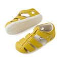 A pair of Bobux Step Up SU Toddlers Tidal Mango Mint Yellow Closed Toe Sandals featuring white soles, open toes, and a closed heel. Made from water-friendly leather, one sandal stands upright while the other rests on its side to showcase the textured sole—ideal as first walker sandals for adventurous little explorers., 9420074808639, 9420074808646, 9420074808707