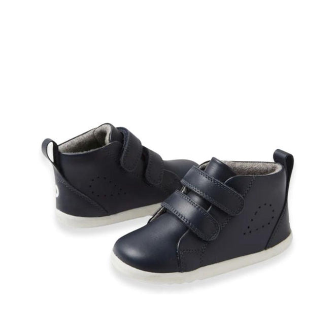 A pair of Bobux Step Up Grass Court Hi Boot Navy toddler sneakers with white soles, two Velcro straps, and a pull tab at the heel, displayed on a white background.