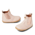 The Bobux Step Up Jodhpur Boot in Cameo Rose Pink is a light pink unisex leather toddler boot with elastic side panels, tan rubber soles, and front/back pull tabs—perfect stylish first walkers.