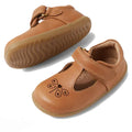 The Bobux Step Up T-Bar Rosie First Walker Shoe in Caramel Tan is a light brown toddler leather flat with Velcro straps, rubber soles, and a butterfly cut-out with heart on the toe—ideal for first walkers. One shoe stands upright, one lies on its side.