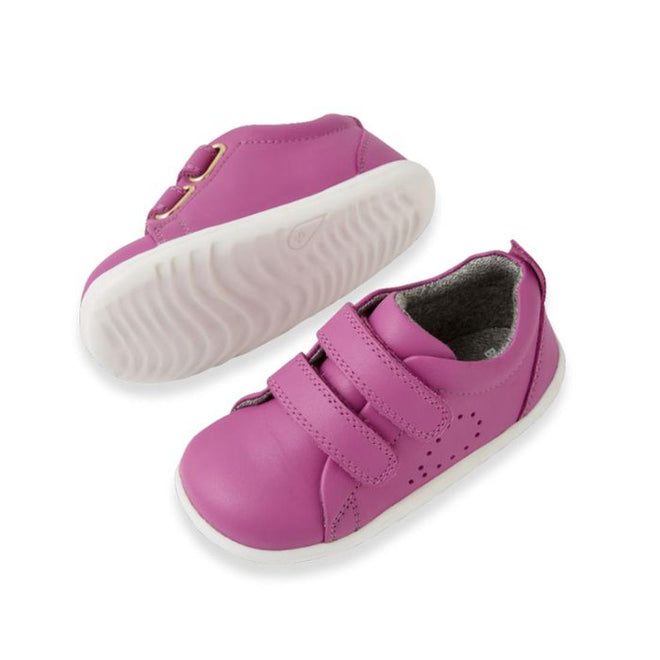 A pair of small, bright orchid purple Bobux Step Up Grass Court Trainer leather shoes with white soles and two velcro straps, shown on a white background. Perfect as stylish first walker shoes for your little one., 9420074806499, 9420074806505, 9420074806512, 9420074806529