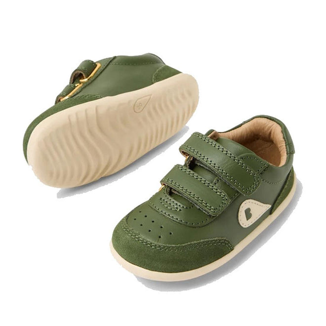 The Bobux Step Up SU Champ II Sneaker in Bronze Green is a pair of toddler leather shoes with beige soles, adjustable hook-and-loop straps, and a small heart detail on the side. One shoe is shown from the top, the other from the sole., 9420074812698, 9420074812704, 9420074812711