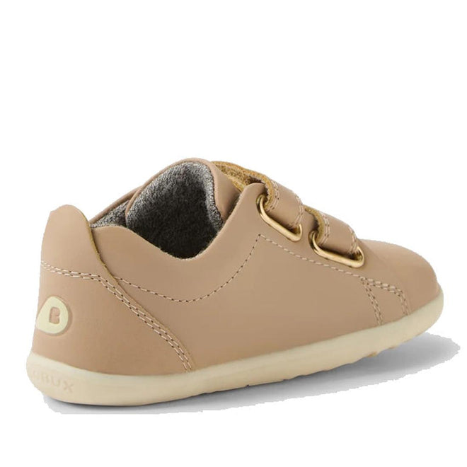The Bobux Step Up Grass Court Trainer Warm Taupe Shoes are tan leather toddler sneakers with beige soles, gold eyelets, tan laces, visible stitching, a soft gray lining, and a B logo—ideal first walker shoes for stylish little ones., 9420074802033, 9420074802040, 9420074802057