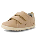 The Bobux Step Up Grass Court Trainer Warm Taupe Shoes are toddler leather sneakers in tan, featuring two velcro straps, a white rubber sole, and decorative side perforations—ideal first walker shoes for little ones., 9420074802033, 9420074802040, 9420074802057