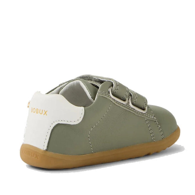 The Bobux SU Step Up Maverick Leather Toddlers Sneaker in Vetiver Green is a small olive-green first walker with a white heel, light brown sole, and adjustable Velcro strap. "BOBUX" is printed in gold on the back white heel tab., 9420074836649, 9420074836656, 9420074836663