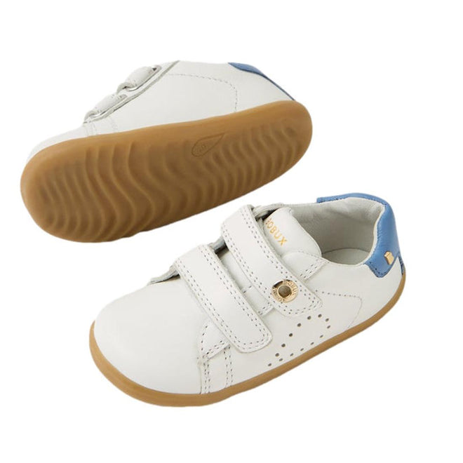 The Bobux SU Step Up Maverick Leather Toddlers Sneaker in White Coronet Blue features white leather, blue heel accents, light brown soles, and two velcro straps—perfect breathable first walker shoes for toddlers. One shoe shown from the side, one sole view., 9420074836793, 9420074836809, 9420074836816