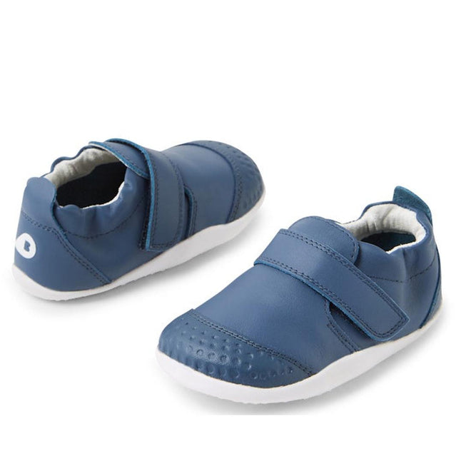 The Bobux XP Xplorer First Walking Shoes Go Vintage Indigo Blue are pre-walker leather shoes with white soles and Velcro straps, featuring a flexible sole for comfort—ideal for your toddler's first steps.