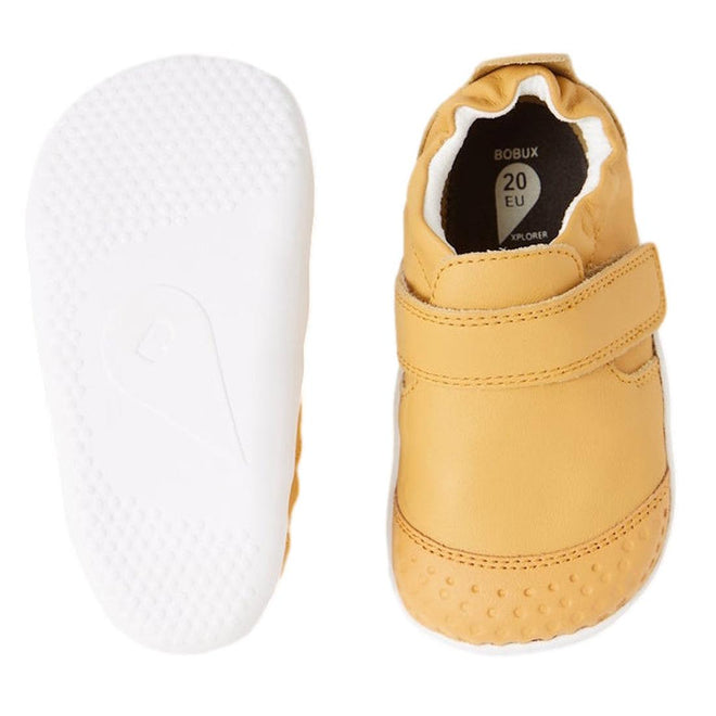 The Bobux XP Xplorer First Walking Shoes Go Oak Buff Tan are pre-walker leather shoes for first steps, shown from the side and sole. One displays a white flexible sole, the other features a velcro strap and soft, rounded toe., 9420068567962, 9420068567979, 9420068567986