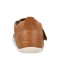 A back view of the Bobux Explorer Marvel Caramel Dress Shoe First Walker shows its brown leather, white sole, stitched logo on the heel, and side strap.