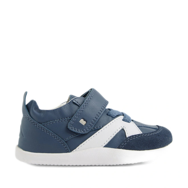 Introducing the Bobux Xplorer XP Chase Vintage Indigo Blue First Walker Crawler—a stylish baby sneaker featuring a blue and white color scheme with a white sole, navy toe cap, and convenient Velcro strap across the top. Perfect for first walkers, this design includes matching blue laces and a small silver heart accent on the strap., 9420074850638, 9420074850645, 9420074850652, 9420074850669
