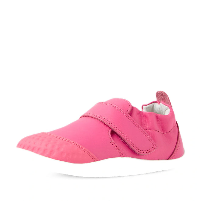 The Bobux Xplorer XP Go Pink Lemonade First Walker Crawler is a soft leather baby shoe in pink with a Velcro strap and a white sole, displayed from a front-side angle on a white background—perfect for toddlers as their first walker shoes., 9420074809032, 9420074809049, 9420074809056
