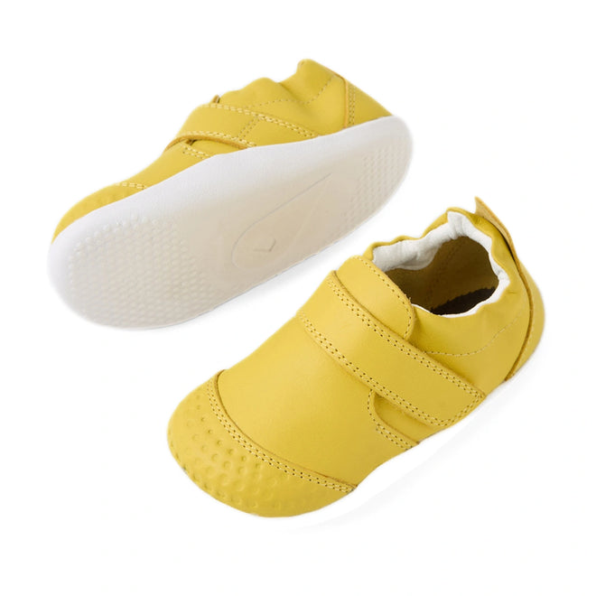 A pair of Bobux Xplorer XP Go Mango Mint First Walker Crawler infant shoes in yellow with white soles, featuring a hook-and-loop strap and textured toe area. One shoe is upright while the other displays the sole., 9420074809339, 9420074809346, 9420074809353