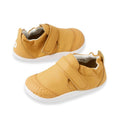 The Bobux XP Xplorer First Walking Shoes Go Oak Buff Tan are small tan pre-walker leather shoes with white flexible soles, velcro straps, and textured toe caps—perfect for your baby's first steps and shown against a white background.
