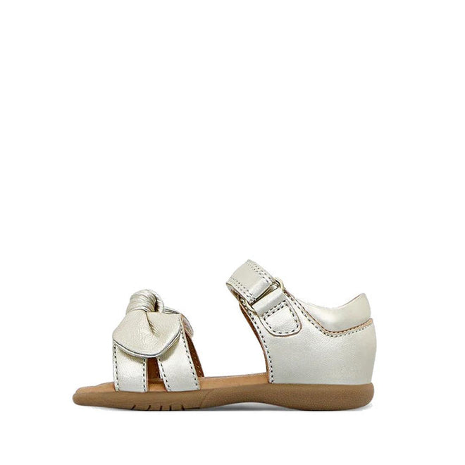 The Clarks Samara Toddlers Gold Leather Sandal in narrow width features an open toe, ankle strap, decorative front bow, tan sole with white stitching, and is shown on a white background., 40541, 9336078235183, 9336078235220, 9336078235268, 9336078235305, 40546, 40547, 40548, 40549, 40532, 9336078234926, 9336078234940, 9336078234964, 9336078234988, 9336078235008, 9336078235022, 9336078235046, 9336078235060