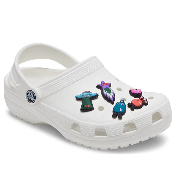 The Crocs Jibbitz 5 Pack - Space Cadet decorates a white Crocs clog with colorful space-inspired charms like a blue creature, red crab, and "help!" top hat, featuring push-in designs, ventilation holes, and a back strap for playful style., 196265848003