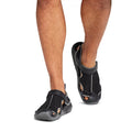 A person wearing Crocs - Mens Swiftwater Mesh Deck LiteRide Sandal Black with cutout sides and thick soles, walking away on a white background. These water-friendly sandals offer a comfortable, casual style, showing only the lower legs and feet., 50133, 50134, 50135, 50136, 50137, 50138, 50139, 50133, 50134, 191448223226, 191448223165, 191448223172, 191448223189, 50139
