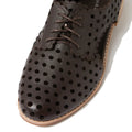 A close-up of the Django & Juliette Adalina Leather Womens Cut Out Brogues Summer Shoes in chocolate brown showcases decorative perforations, scalloped edges, and matching brown laces. Featuring a light-colored sole and a classic brogue design, these shoes embody timeless style and comfort for women.