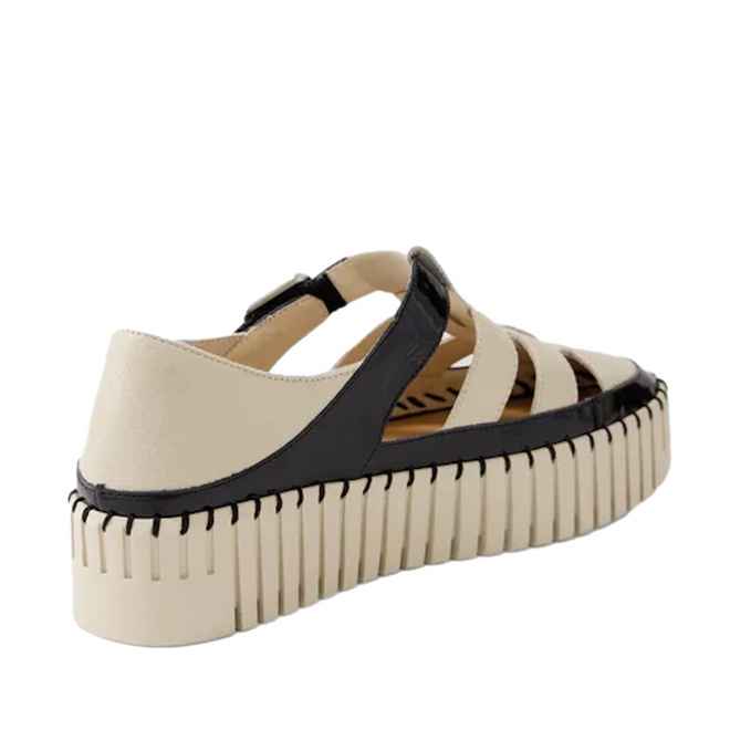 Experience the Django & Juliette Baytown Black Almond Patent Leather Flat, a chic platform sandal inspired by the classic fisherman style. This women’s shoe features wide almond patent leather straps with elegant black trim, a closed heel, open sides, and a thick ridged sole—blending sneaker-inspired flair with timeless sophistication.